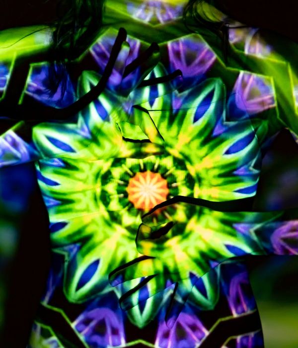 Woman performing a gentle yoga stretch in a dark room with mint green light.